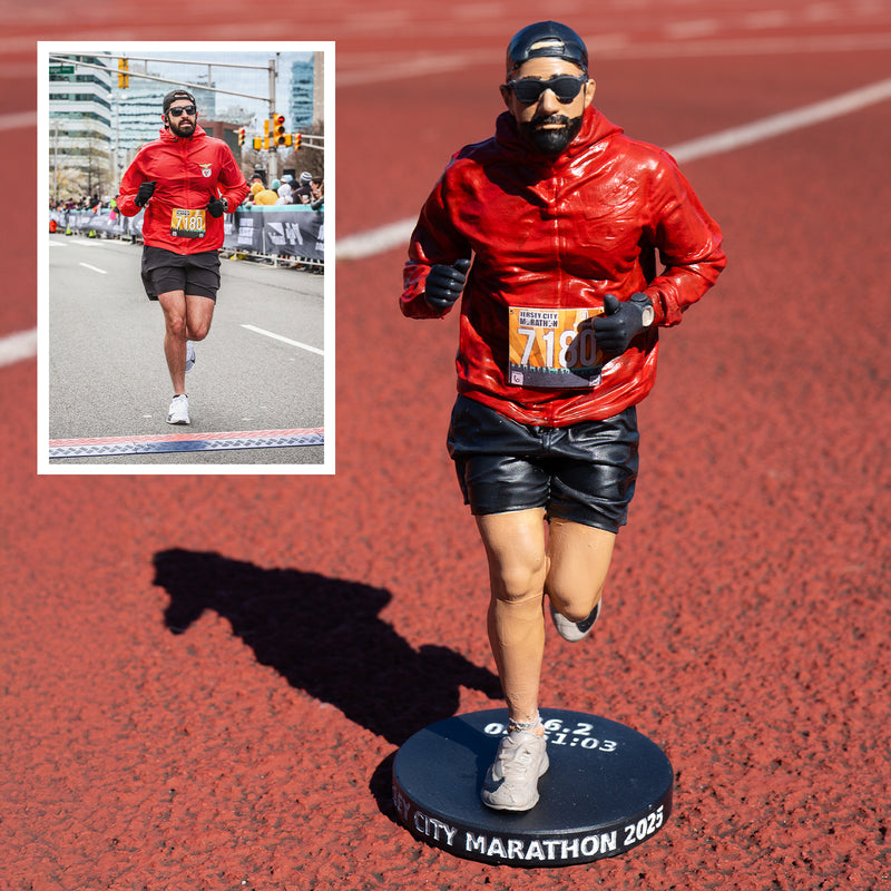 Painted custom figure of a runner in a red jacket and black shorts on an engraved black base, beside the race photo it was made from
